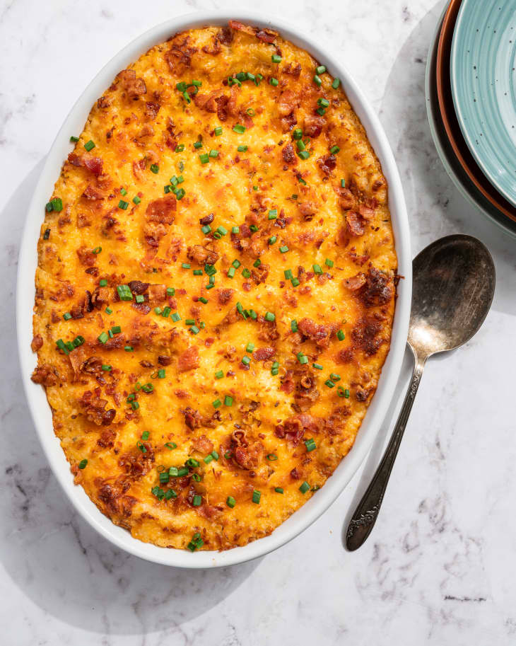 twice baked potato casserole, in a round, white dish, with a spoon next to it
