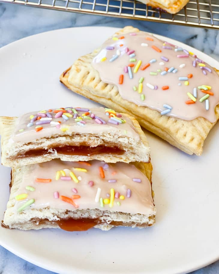 Homemade Pop Tarts with pink icing and pastel rainbow sprinkles on a white plate