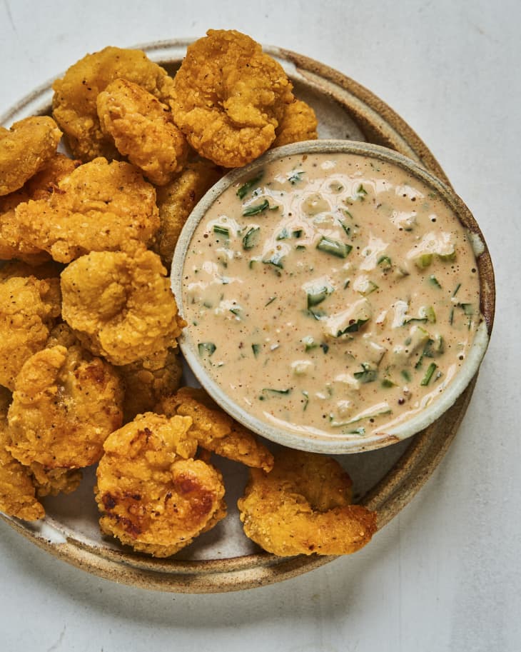Rémoulade (a European cold sauce based on mayonnaise. Although similar to tartar sauce, it is often more yellowish, sometimes flavored with curry, and sometimes contains chopped pickles or piccalilli. It can also contain horseradish, paprika, anchovies, capers and a host of other items) on a plate with breaded and fried shrimp
