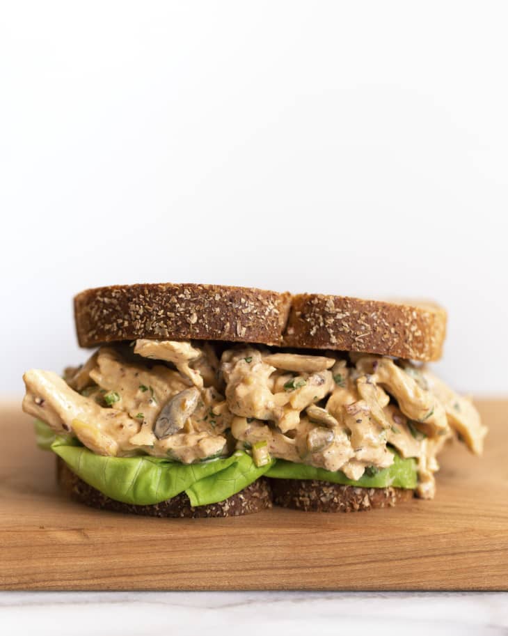 Turkey salad sandwich made with leftover turkey, on a sliced grain bread with lettuce, on a wooden cutting board