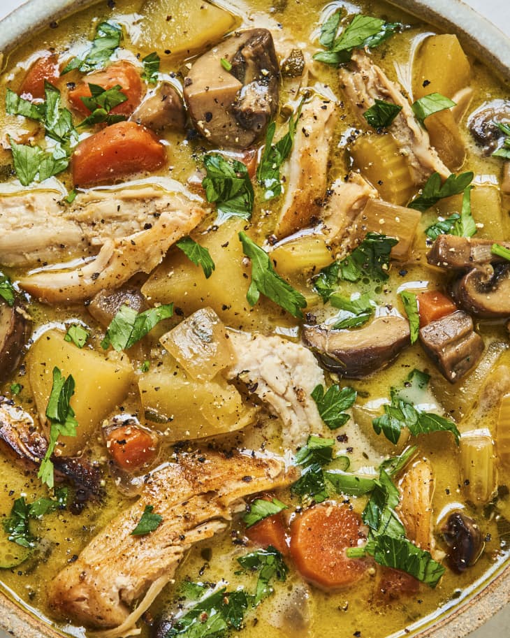 A closeup of Turkey Stew, with shredded turkey, tomatoes, carrots, and parsley in a broth.