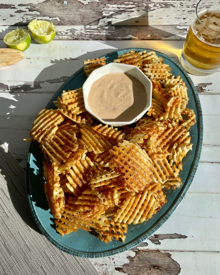 Waffle fries on a blue plate with dipping sauce