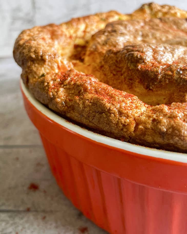 Corn Souffle, seen from side, in a bright orange-red baking dish