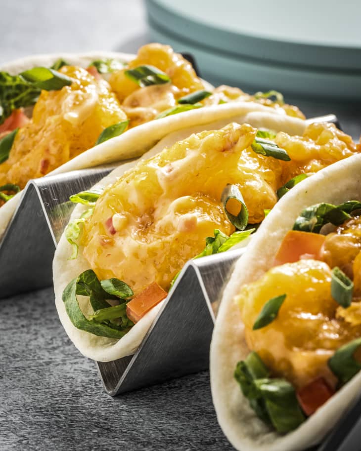 Bang Bang Shrimp (shrimp with a sweet Thai coconut curry sauce) inside of three tacos sitting in a metal taco rack