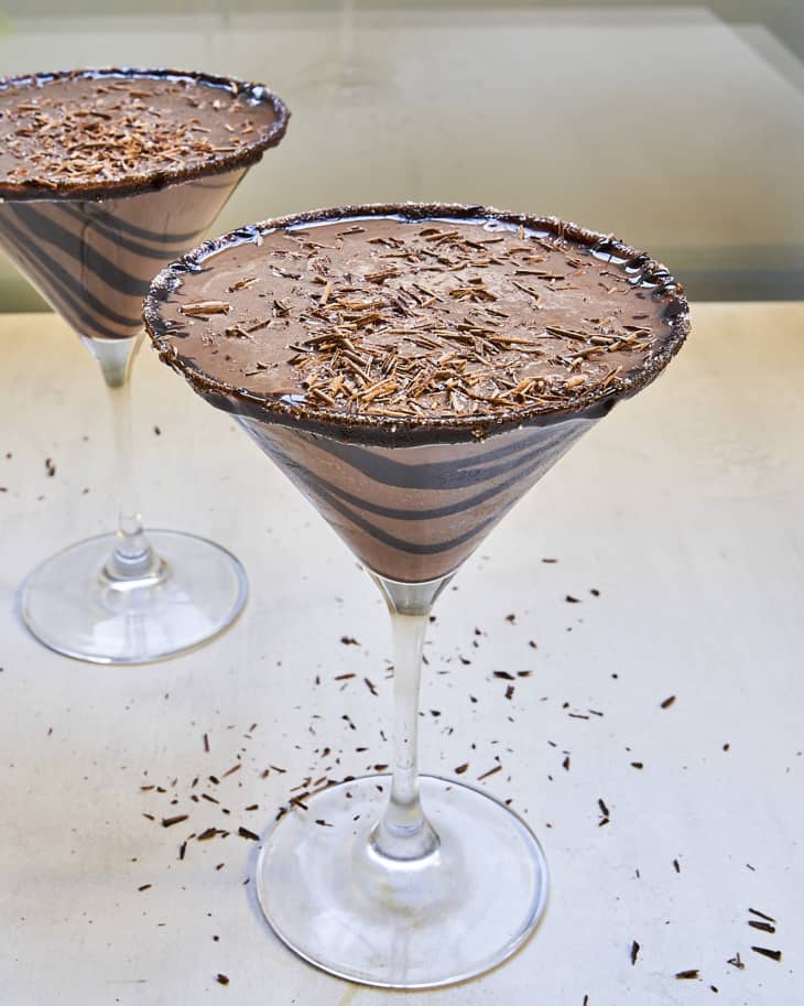 a chocolate martini in a martini glass with a chocolate swirl around the glass and chocolate shavings on top.