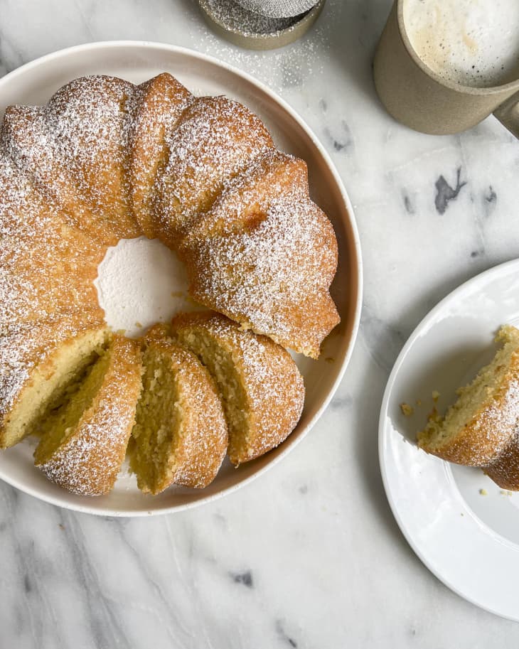 Ciambella (an Italian round cake, like Italy's version of a bundt cake, traditionally eaten for breakfast). on a white plate with a few slices cut.