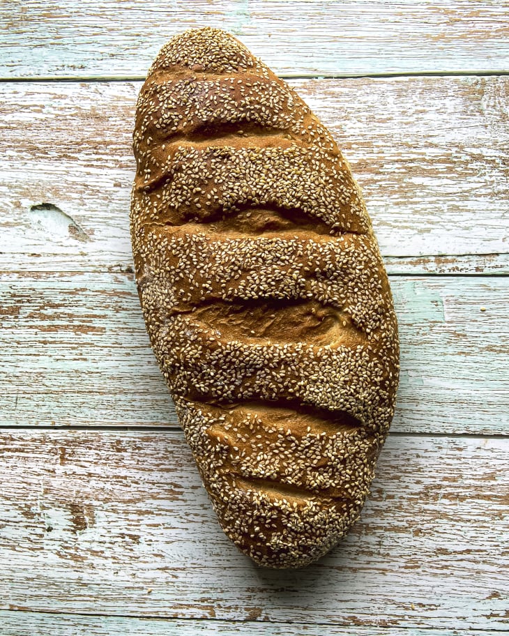 a loaf of italian bread with sesame seeds on a wooden background