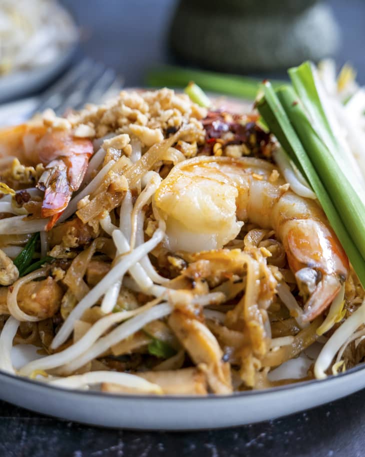 pad thai with shrimp, beansprouts, and green onions, with more of the garnishes in plates on the side.