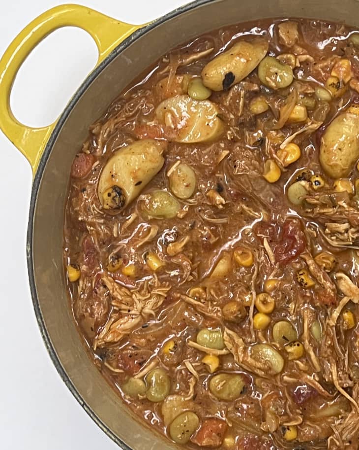 Brunswick stew (a Southern dish that features a tomato base with beans, vegetables, and meat) in a cooking pot with a yellow handle.