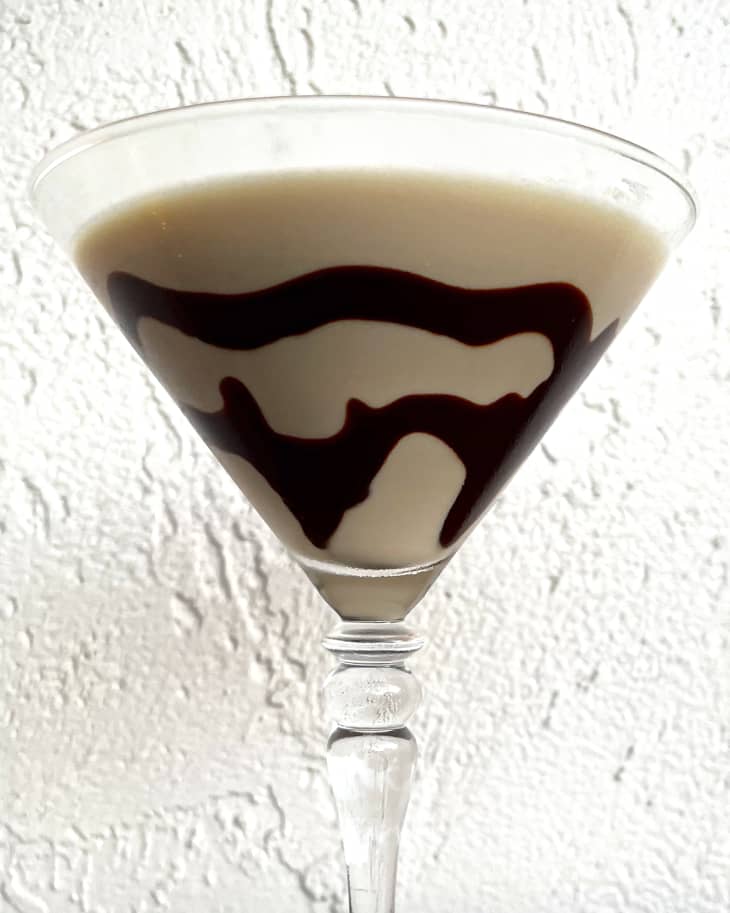 A mudslide alcoholic cocktail in a martini glass with a chocolate swirl.