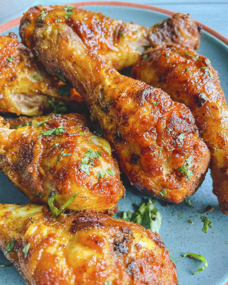 a close up of a pile of air fryer chicken drumsticks on a turquoise plate