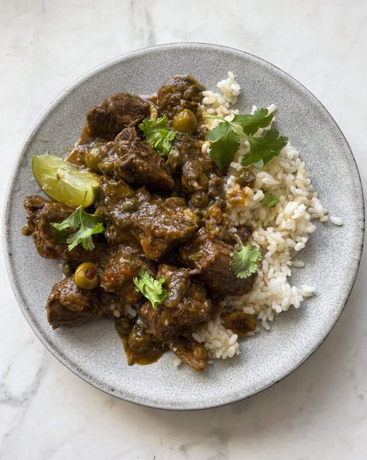 Carne guisada (beef stew made from beef chuck or round that is slowly cooked at low heat until tender) on a white plate with white rice.