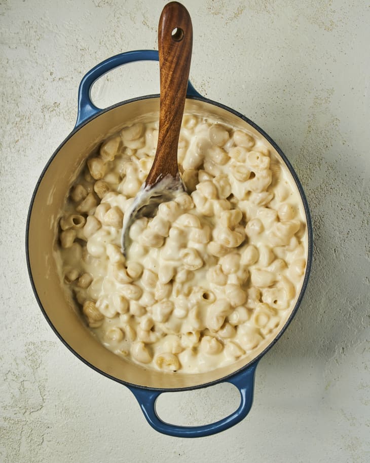 Copycat panera bread mac and cheese in a blue bowl with a wooden serving spoon inside the bowl