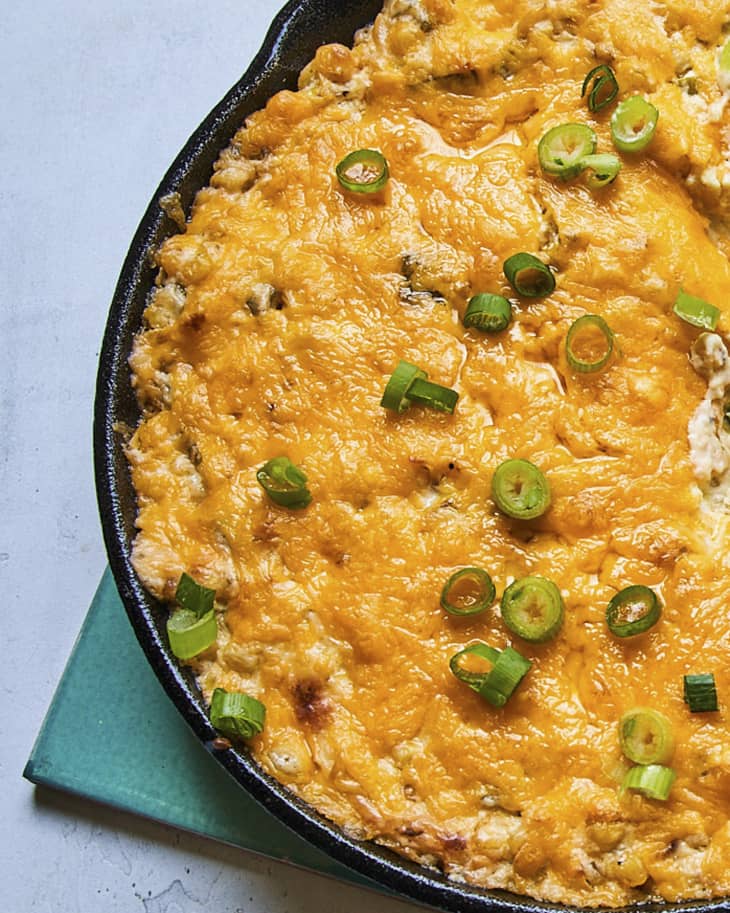 Corn dip is a spin on classic baked dips that uses a cream cheese, mayonnaise, and sour cream base to create a creamy and cheesy concoction. The other flavors accent and build upon the base, here green chile, garlic, scallion, lime, and cheddar cheese