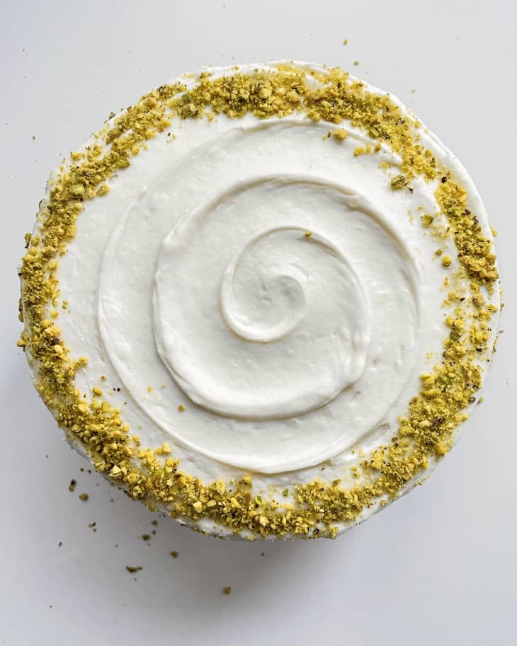 a round Pistachio cake with white icing, seen from the top.