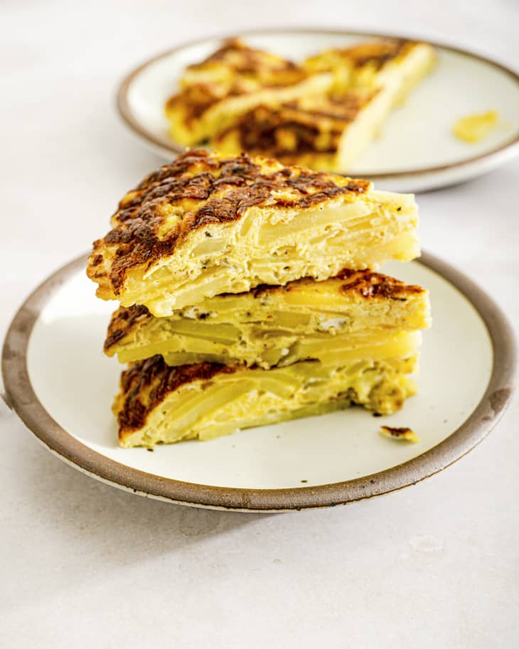 a slice of a Spanish Omelette on a plate. (A Spanish Omelette as seen from above (Spanish omelette or Spanish tortilla is a traditional dish from Spain. Celebrated as national dish by Spaniards, it is an essential part of the Spanish cuisine. It is an omelette made with eggs and potatoes, optionally including onion. It is often served at room temperature as a tapa.)