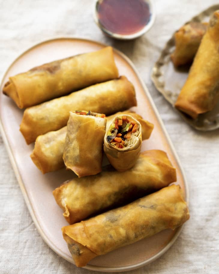 six fried vegetarian spring rolls with one cut in half and leaned on top of the others