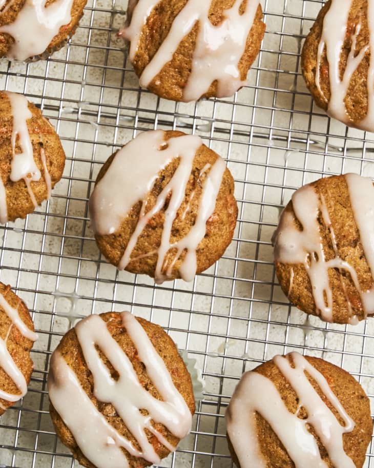carrot cake muffins with white icing on a wire cooling rack