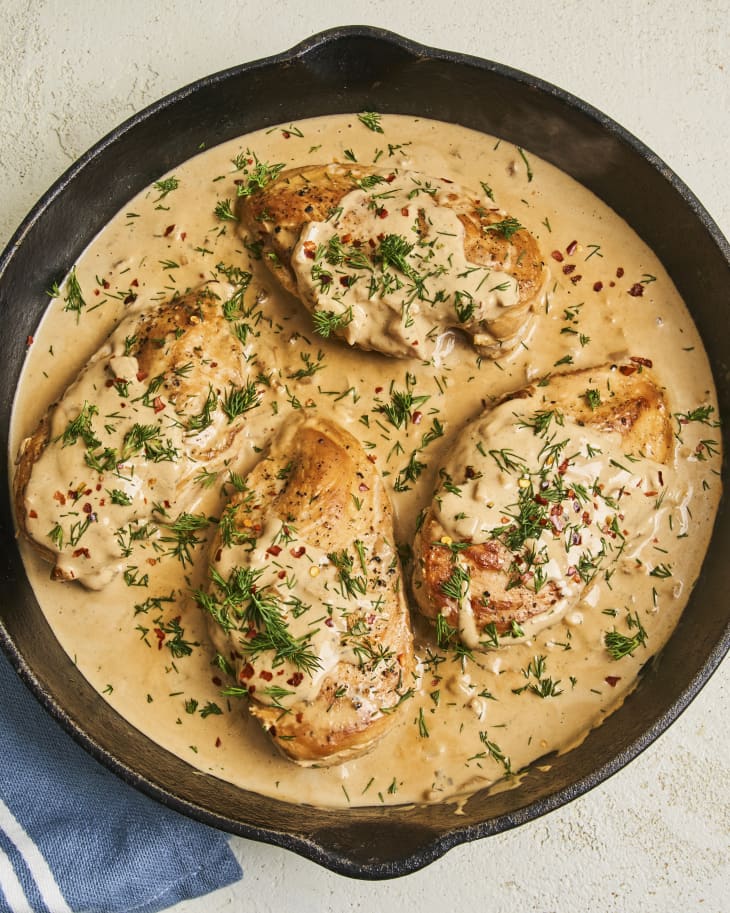 chicken breasts in a creamy light brown sauce in a cast iron skillet