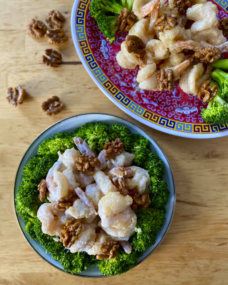Shrimp with honey and walnuts on a small plate with broccoli around the edge of the plate.