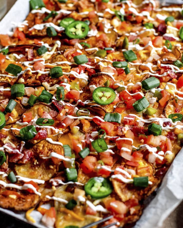 Irish nachos (thinly sliced potatoes, crispy bacon, melted cheese, drizzled sour cream) in a sheet pan