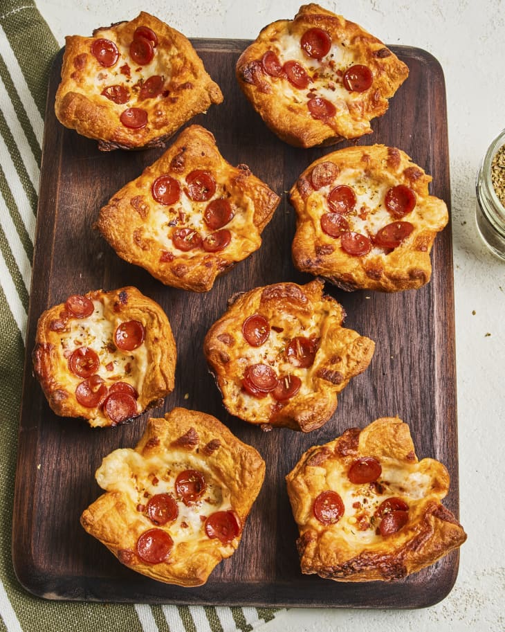 individual pizzas in the shape of cupcakes on a wooden cutting board