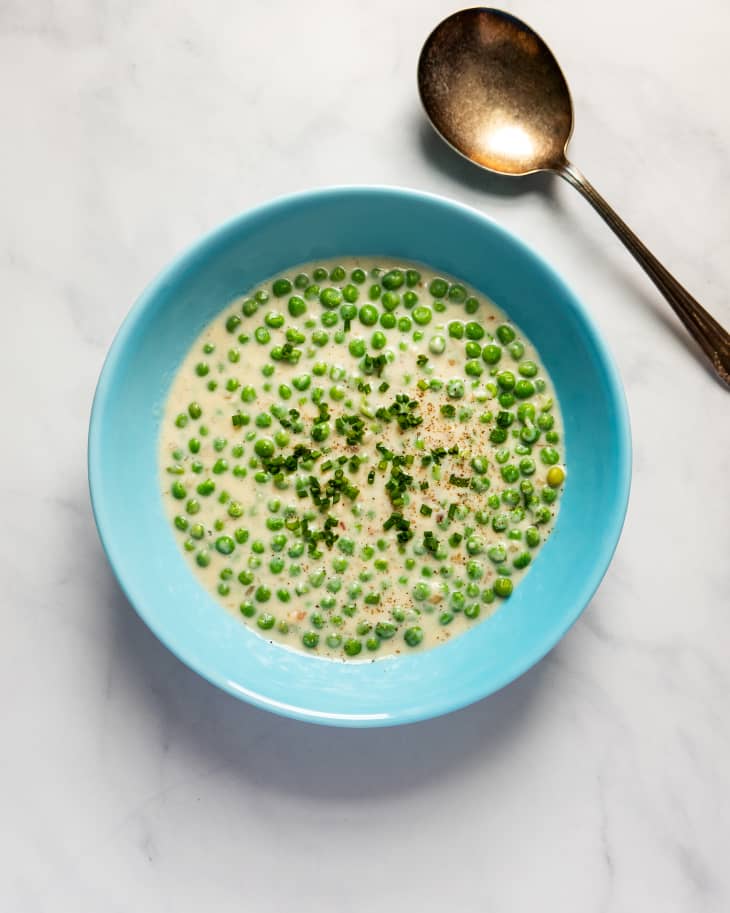 creamed peas in a turquoise bowl with a spoon on the side