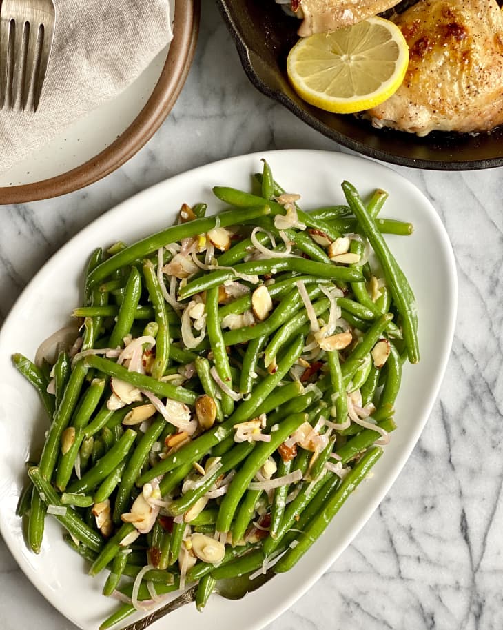 green beans (almondine) with sliced almonds on a white plate