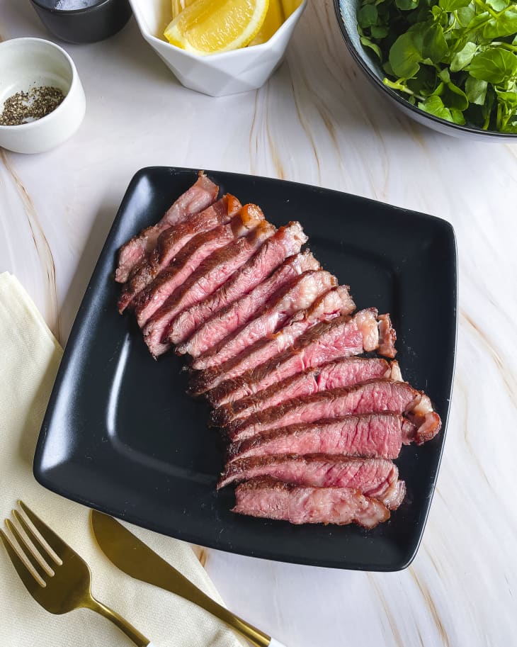 steak cut into thin strips on a square black plate