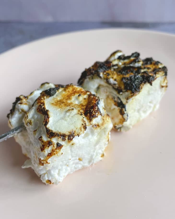 two toasted vegan marshmallows on a plate.