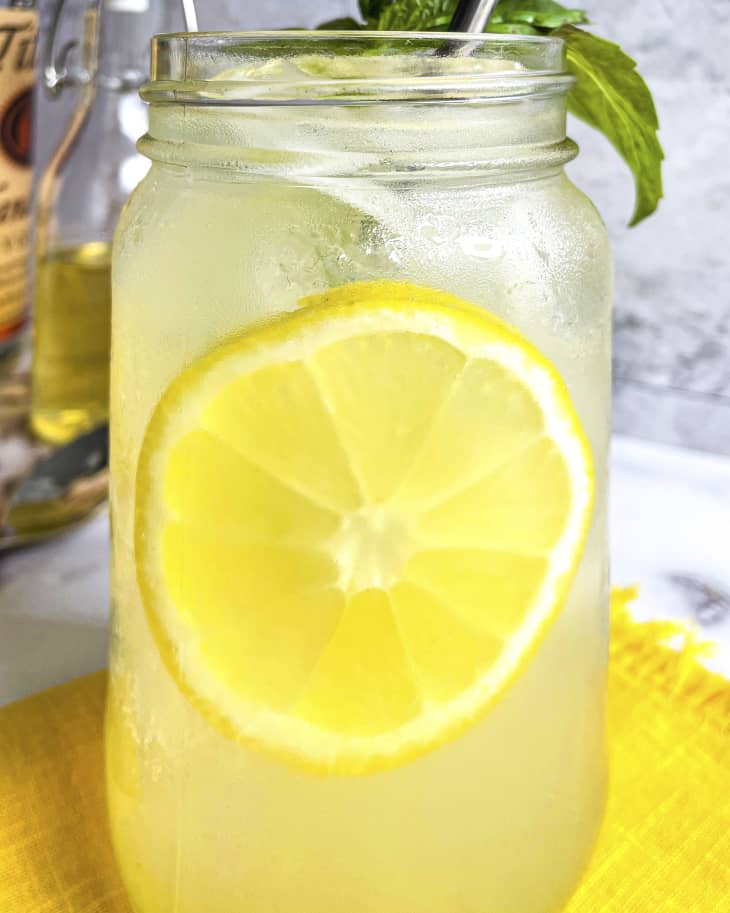 a mason jar with vodka lemonade and a round slice of lemon floating in the middle