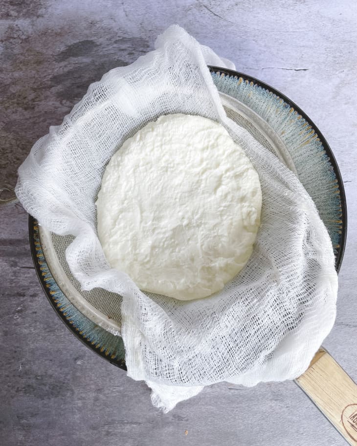 A photo of greek yogurt being strained through cheesecloth into a bowl