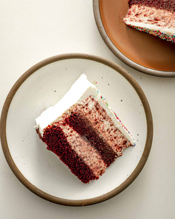 A photo of a slice of layered red velvet ice cream cake, on its side