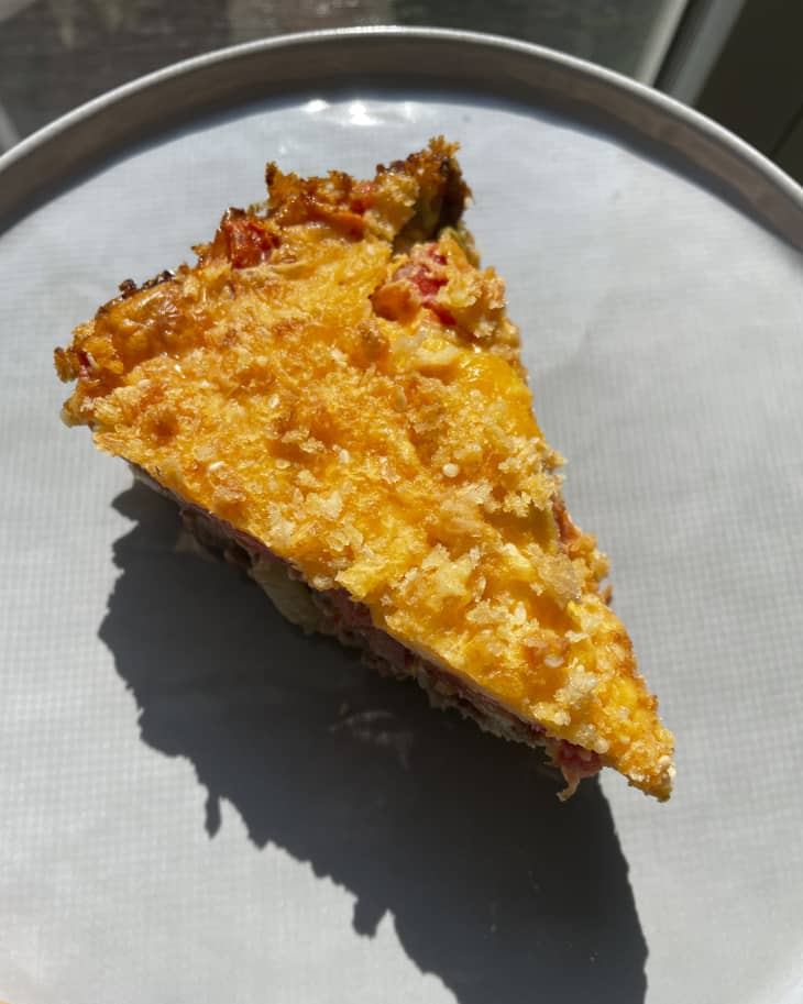 A photo of a slice of cheeseburger pie on a gray plate with a hard shadow.