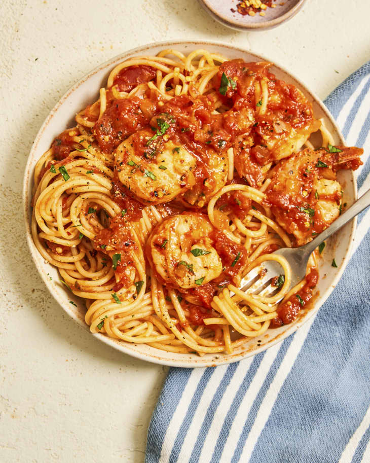 A photo of a bowl of spaghetti tossed with a red Fra Diavlo sauce with shrimp, and a fork resting on the side