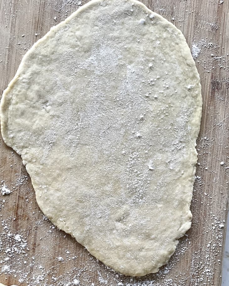 A photo of a piece of empanada dough rolled out with flour on a cutting board.