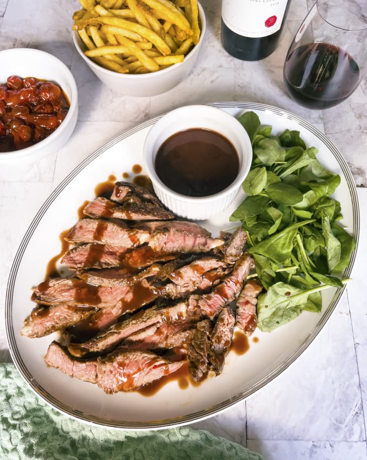 A photo of plate of sliced steak with Bordelaise Sauce (a classic French sauce named after the Bordeaux region of France, which is famous for its wine. The sauce is made with dry red wine, bone marrow, butter, shallots and sauce demi-glace)