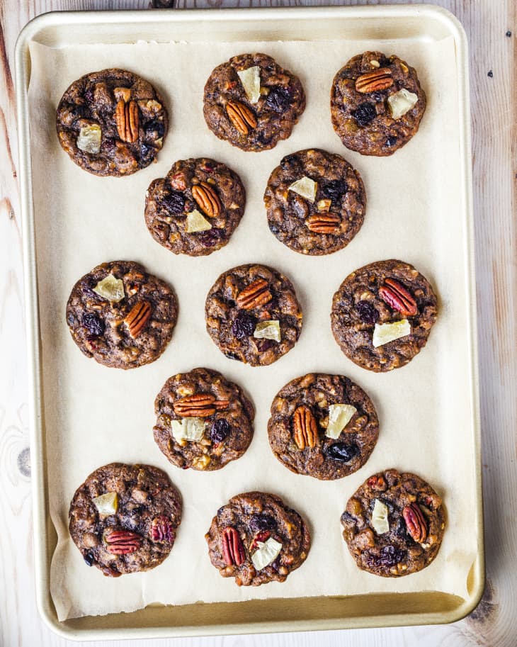 A photo of a baking sheet with parchment paper with fruitcake cookies laid out.
