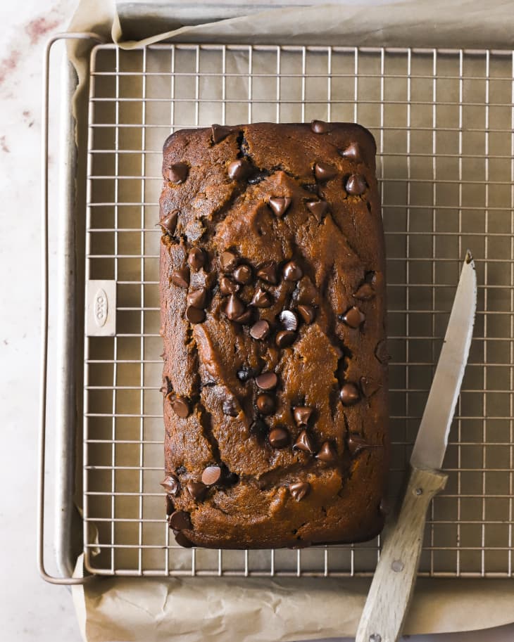 A photo of a loaf of pumpkin chocolate chip bread on a cooling rack.