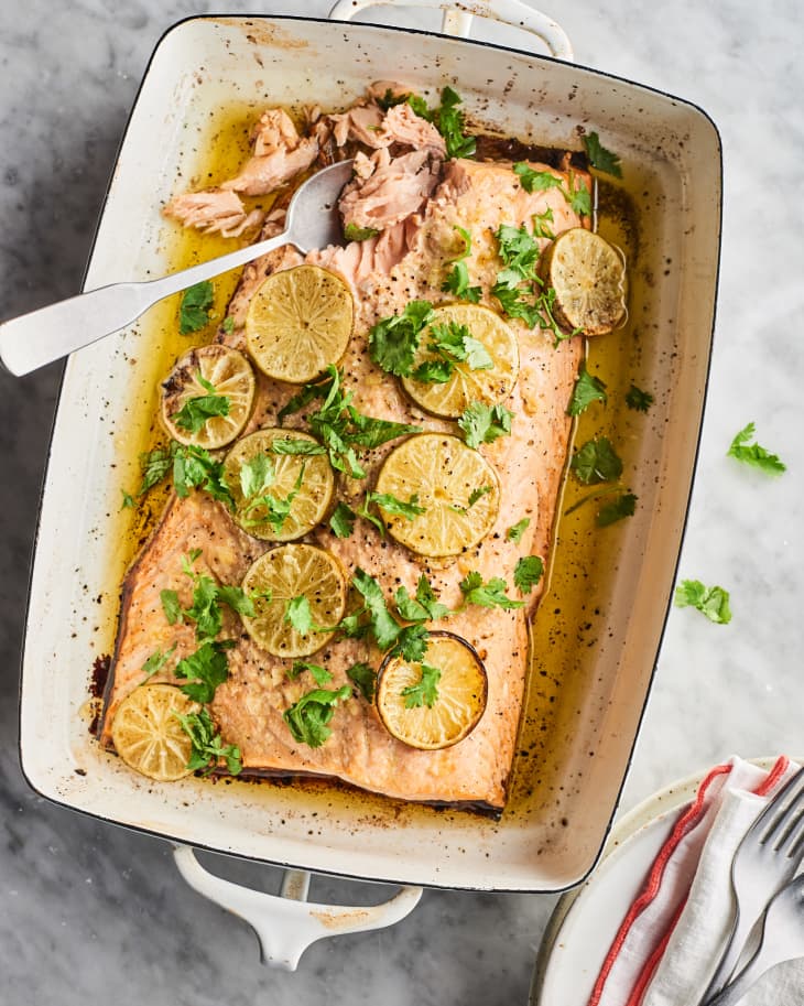 Cooked salmon topped with cilantro and lime in a roasting pan