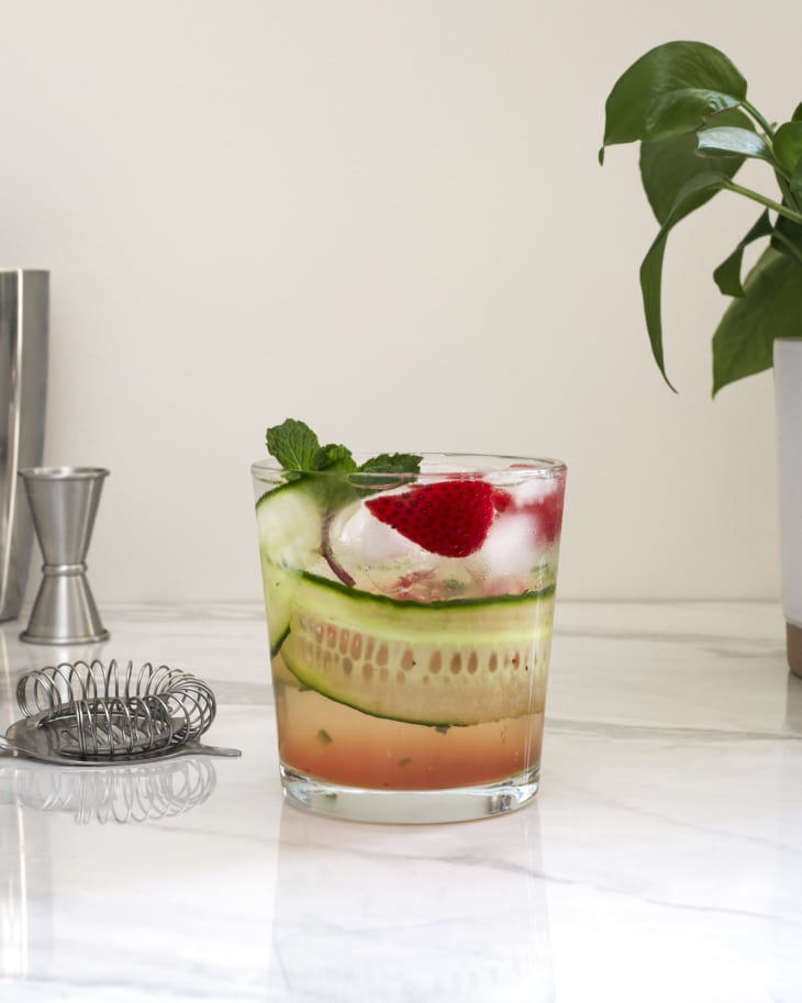 A cocktail in a glass sits on the kitchen counter.