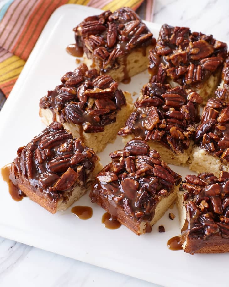 Square slices of the sticky bun sour cream coffee cake sits on a cutting board.