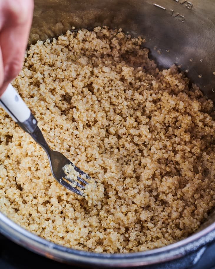 A fork is used to fluff the cooked quinoa in the instant pot.