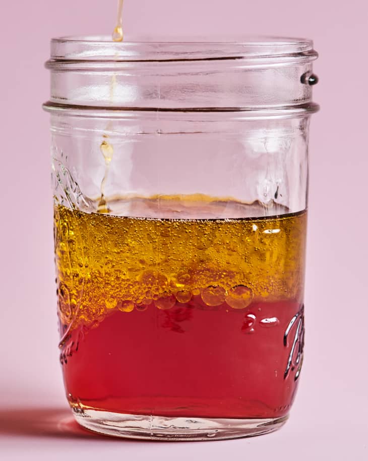 Olive oil sits on top of a 1/2 cup of vinegar in a glass mason jar.