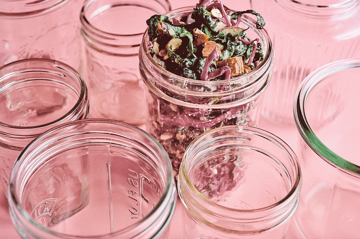 Glass mason jars are filled with salad.