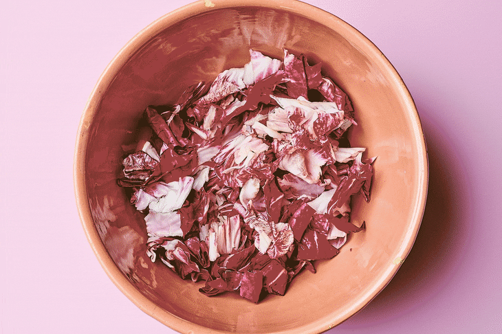Salad is added to a bowl and mixed.