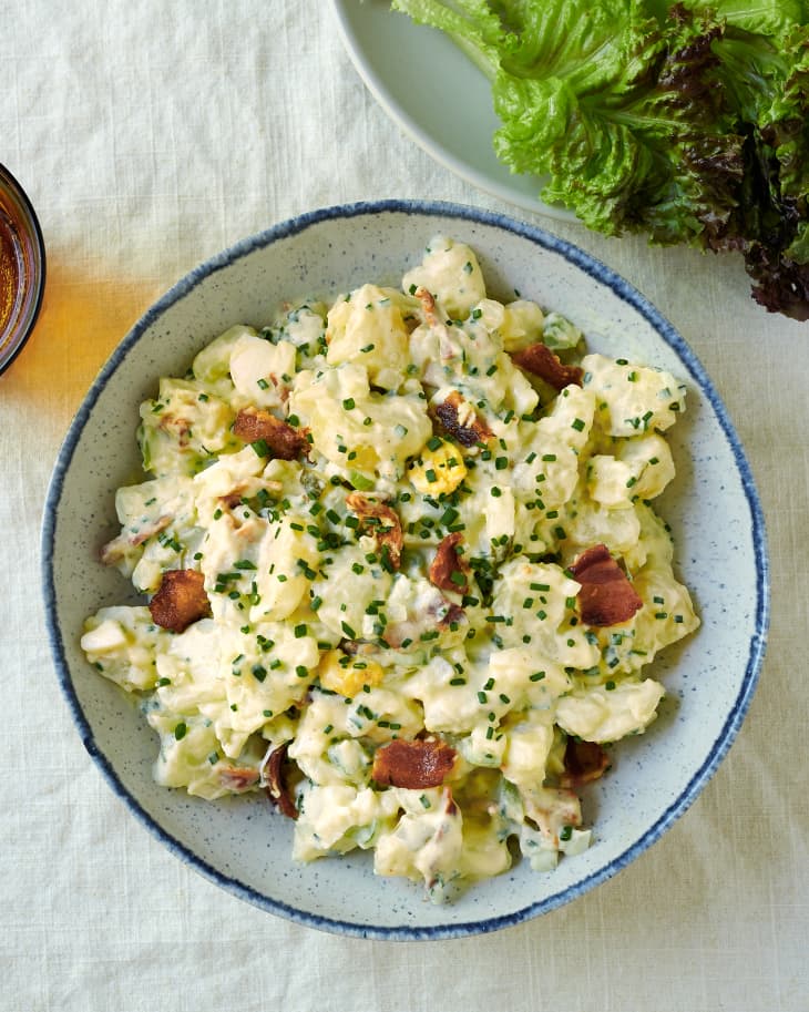 Julia Child potato salad with chives and bacon placed in blue and white speckled bowl