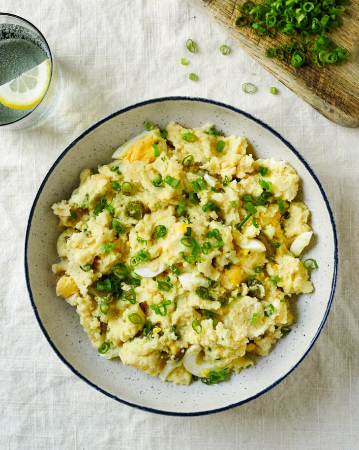 Pioneer Woman's potato salad with egg, chives and pickled in a large white and blue speckled bowl
