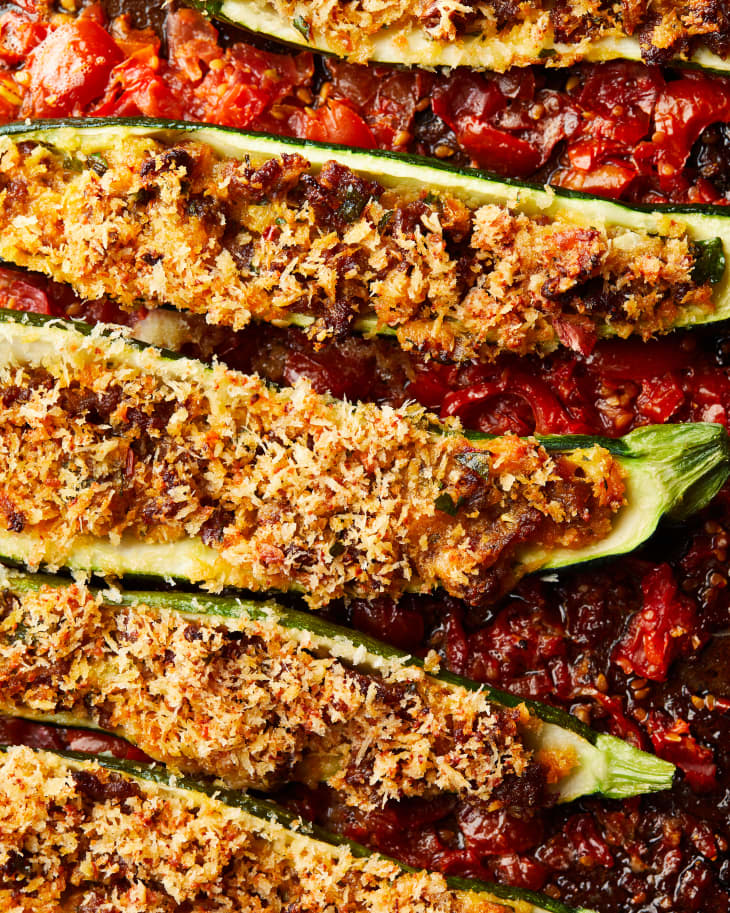 close up shot of cooked crispy, saucy stuffed zucchini on bed of roasted tomato sauce