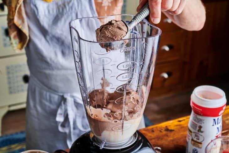 A scoop of chocolate ice cream is put into the blender.
